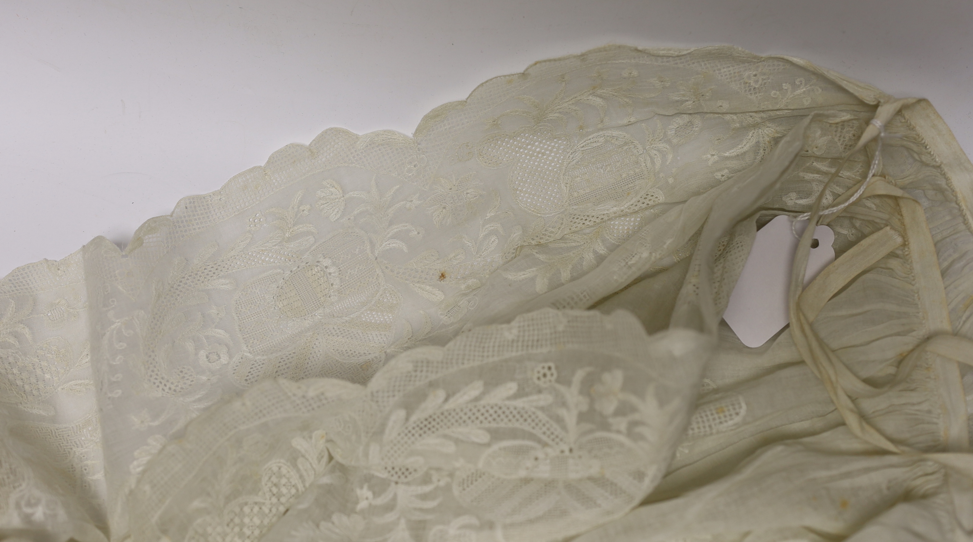 An 18th century Dresden worked apron, a white worked fine lawn stole, two panels of linen ribbon work, a ladies lace bonnet a similar pink satin bonnet a white worked blouse (partially made) and panel to a christening go